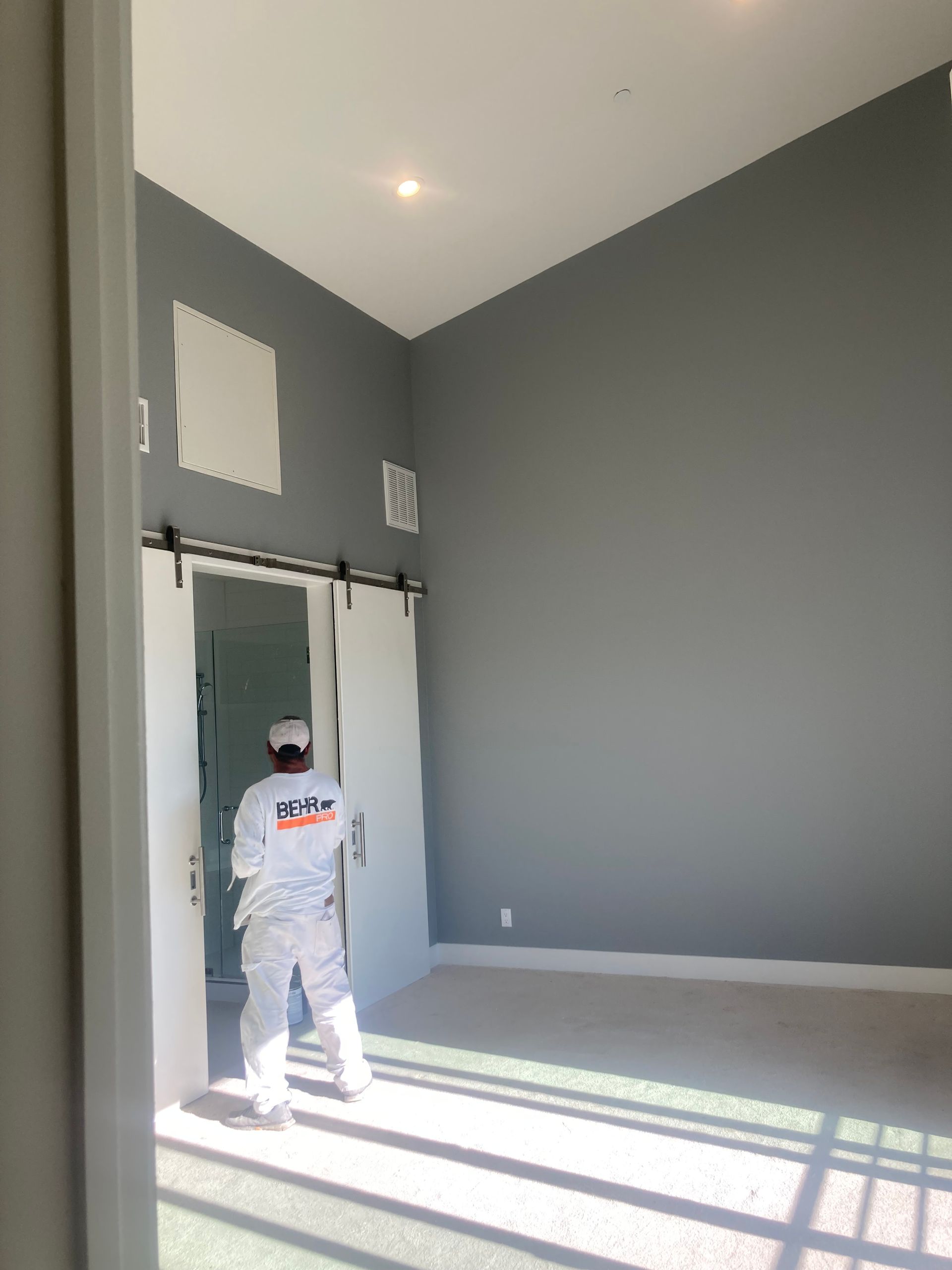A man is standing in an empty room with sliding barn doors.