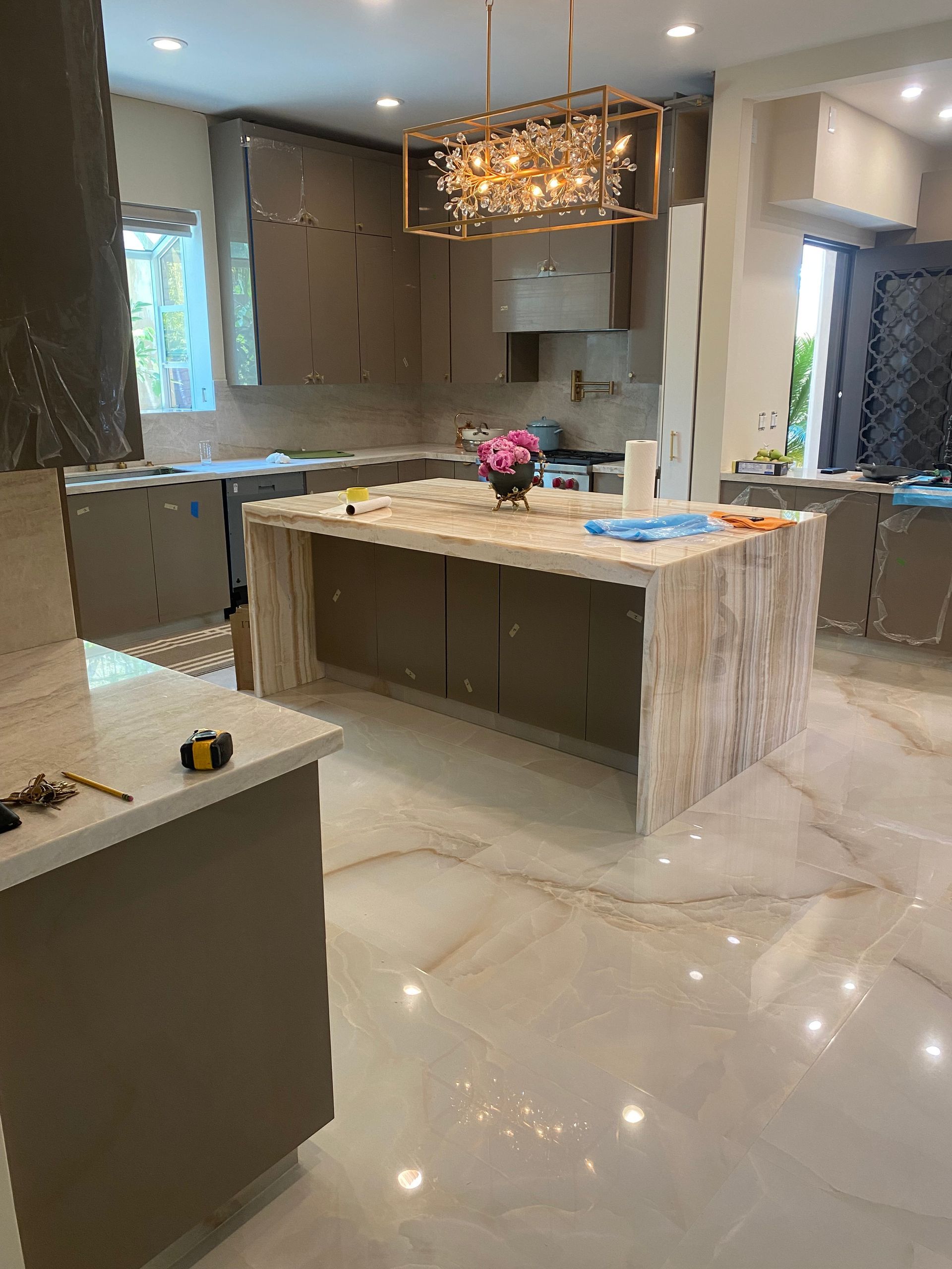 A kitchen with a large island in the middle and a chandelier hanging from the ceiling.