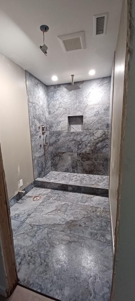 A bathroom with a walk in shower and a ceiling fan.
