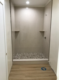 A bathroom with a walk in shower and a wooden floor.