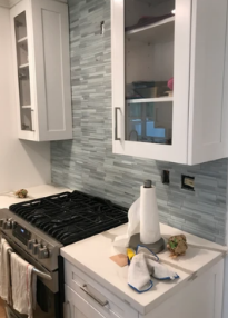 A kitchen with a stove top oven and white cabinets