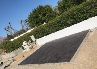 A large concrete slab is sitting on the ground in front of a white wall.