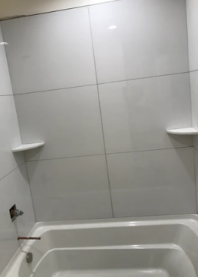 A bathroom with a bathtub , shower , and shelves.