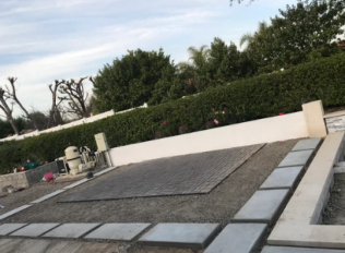 A concrete area with a white wall and trees in the background