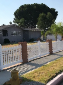 A white fence surrounds a house with a fire hydrant in front of it