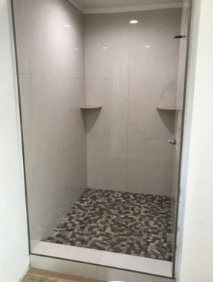 A shower with a glass door and a tiled floor