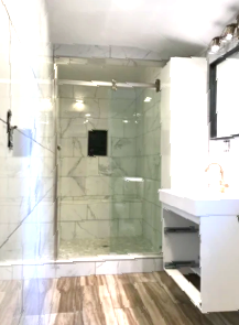 A bathroom with a walk in shower , sink and mirror.