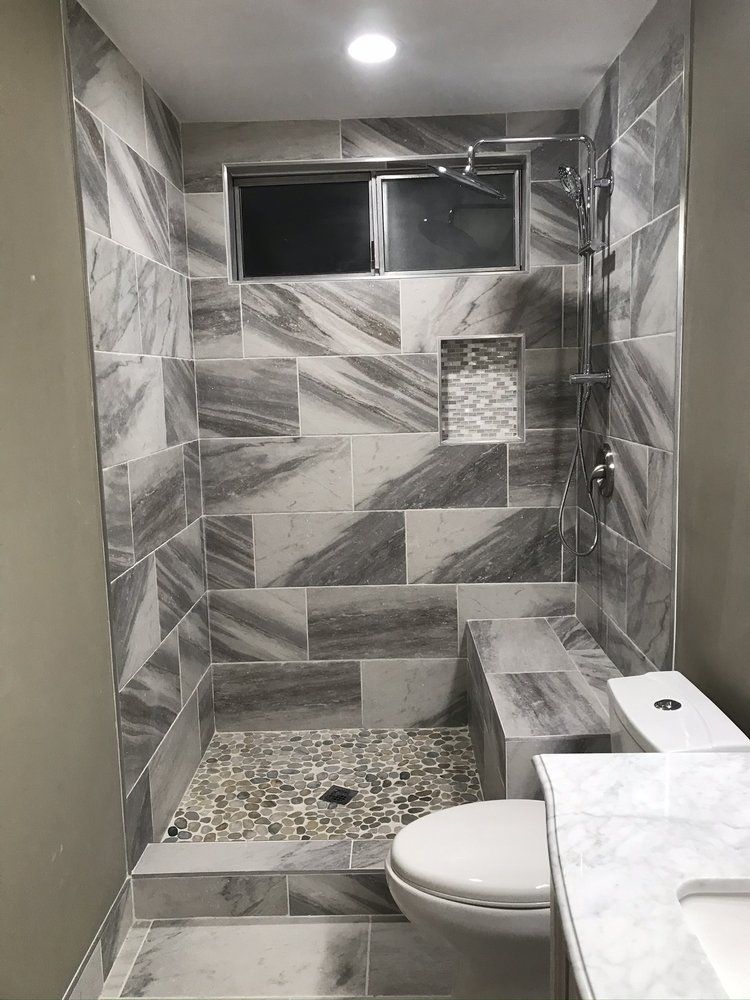 A bathroom with a toilet , sink and tiled shower.