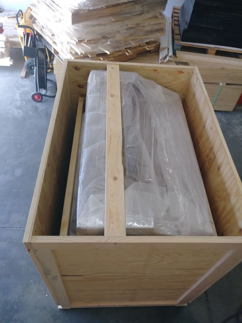 Wooden crate containing a large, plastic-wrapped object.