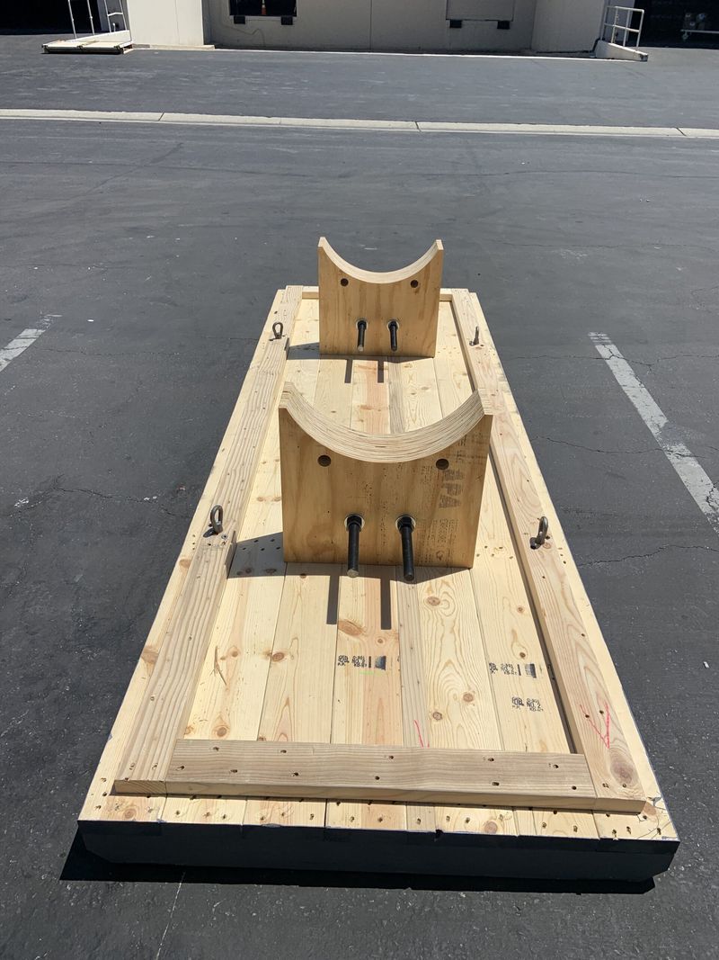 Wooden horse-shoe game board on asphalt. Two wooden uprights with curved tops, surrounded by a border.