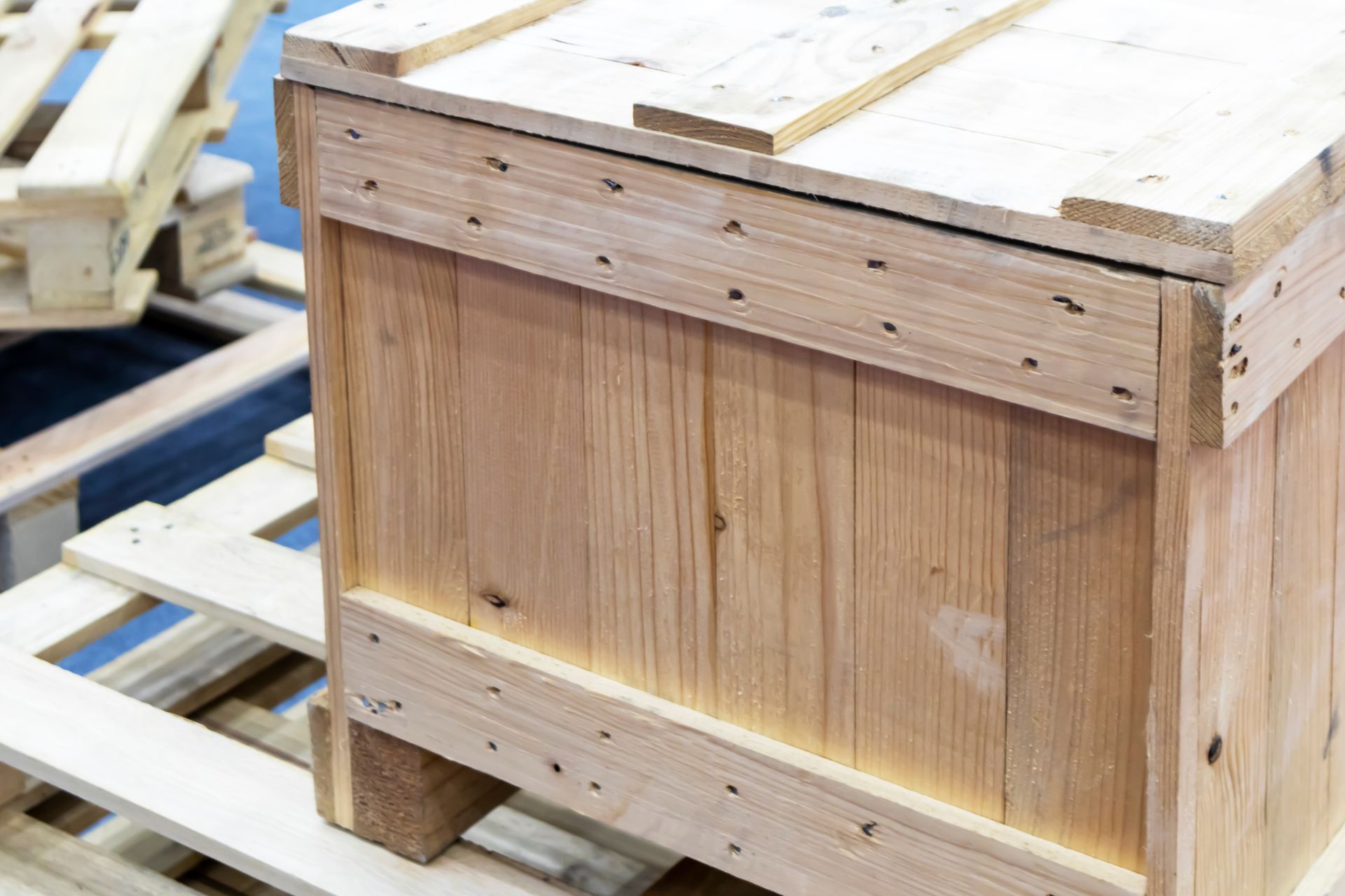 Wooden crate on a wooden pallet. The crate is light brown and has wood grain.