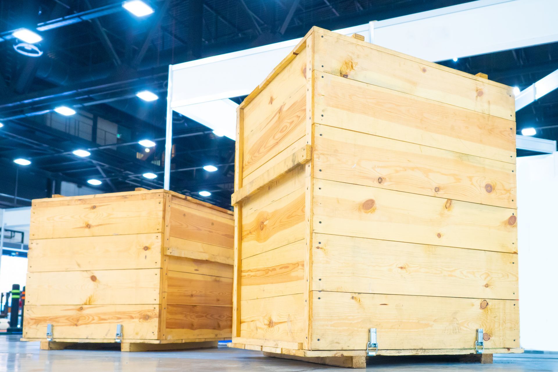Two large wooden shipping crates on a light-colored floor, in an indoor industrial setting.