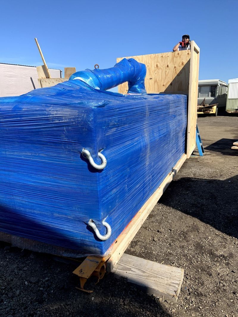Blue tarp covering stacked materials, with metal hooks attached to wooden frame.