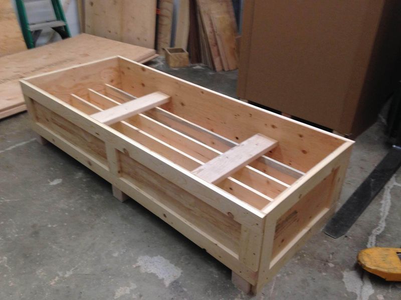 Wooden crate with interior dividers, on a concrete floor.