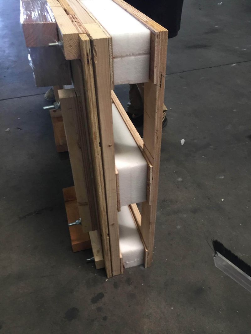 Wooden frame with white foam inserts, likely for packing or shipping.