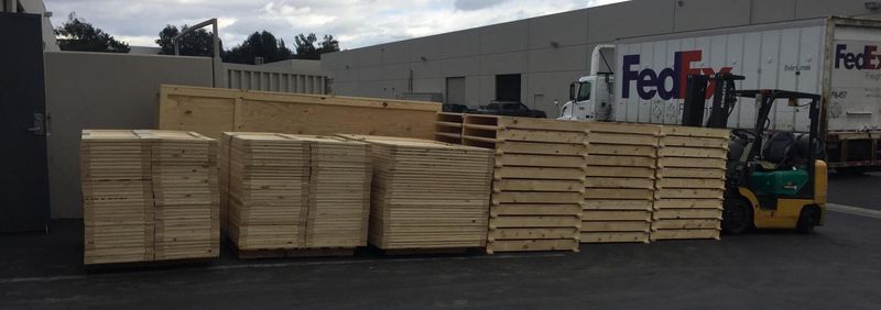 Wooden pallets stacked next to a FedEx truck. A forklift is nearby.
