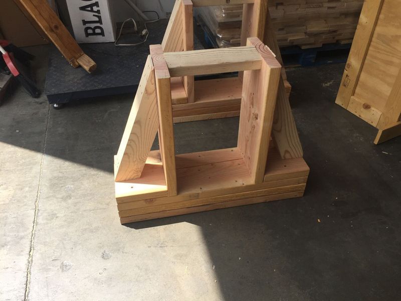 Wooden boat stand, made of layered lumber. In a warehouse setting.