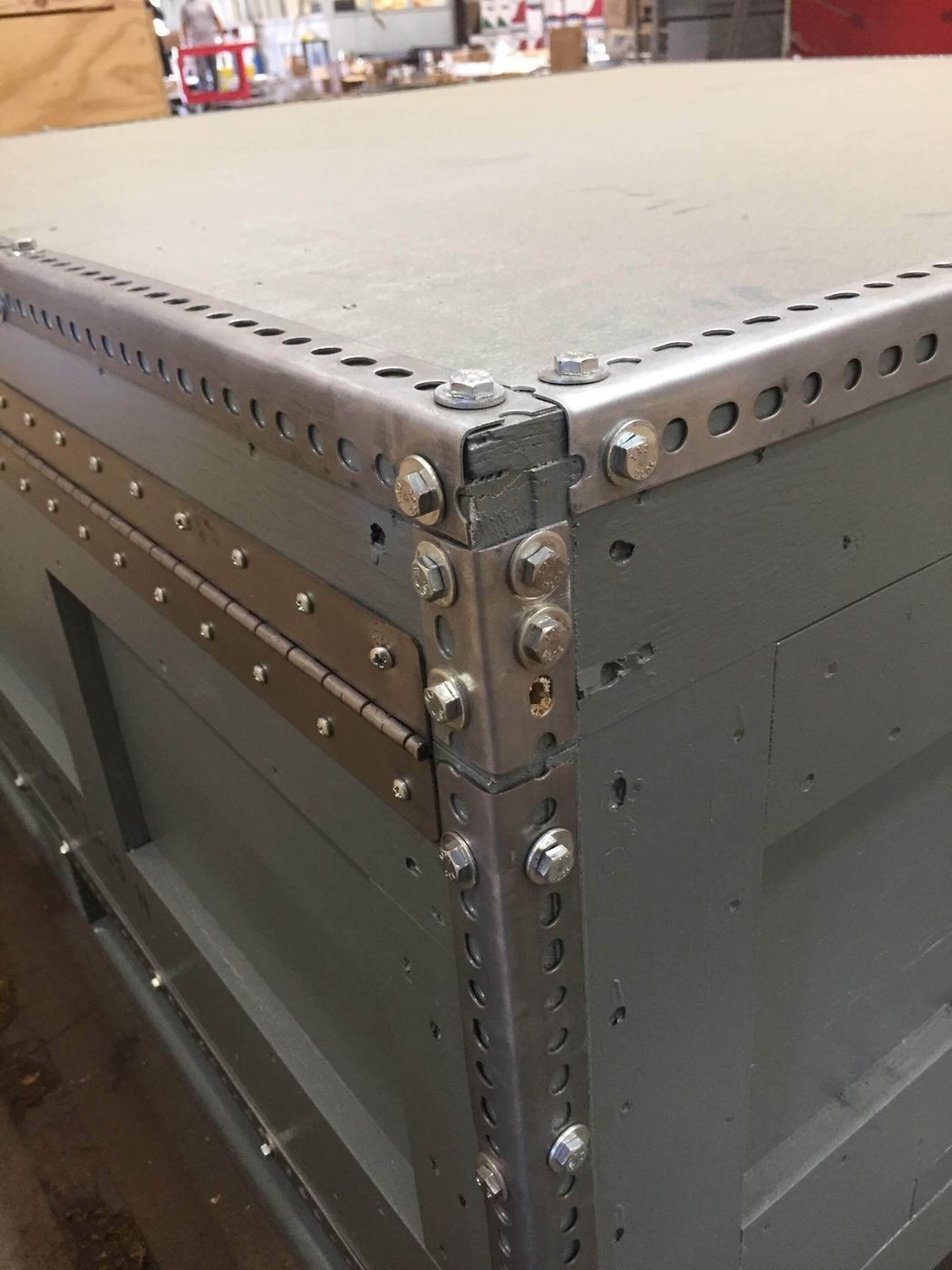 Gray box with metal corner reinforcements and bolted edges.