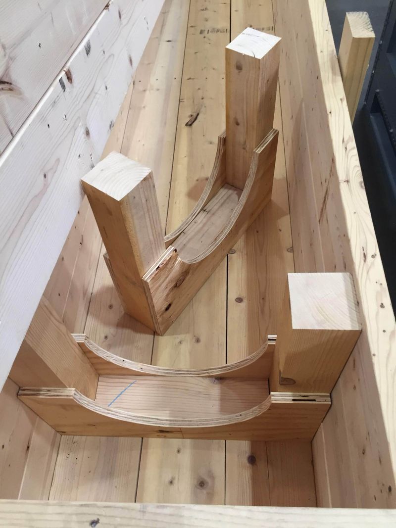 Wooden support structure with curved braces inside a wooden box.