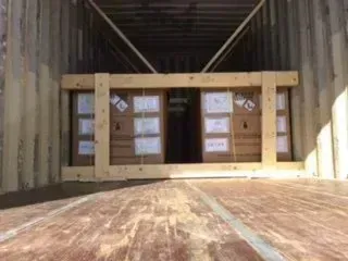 Wooden crate with cardboard boxes inside a cargo container.