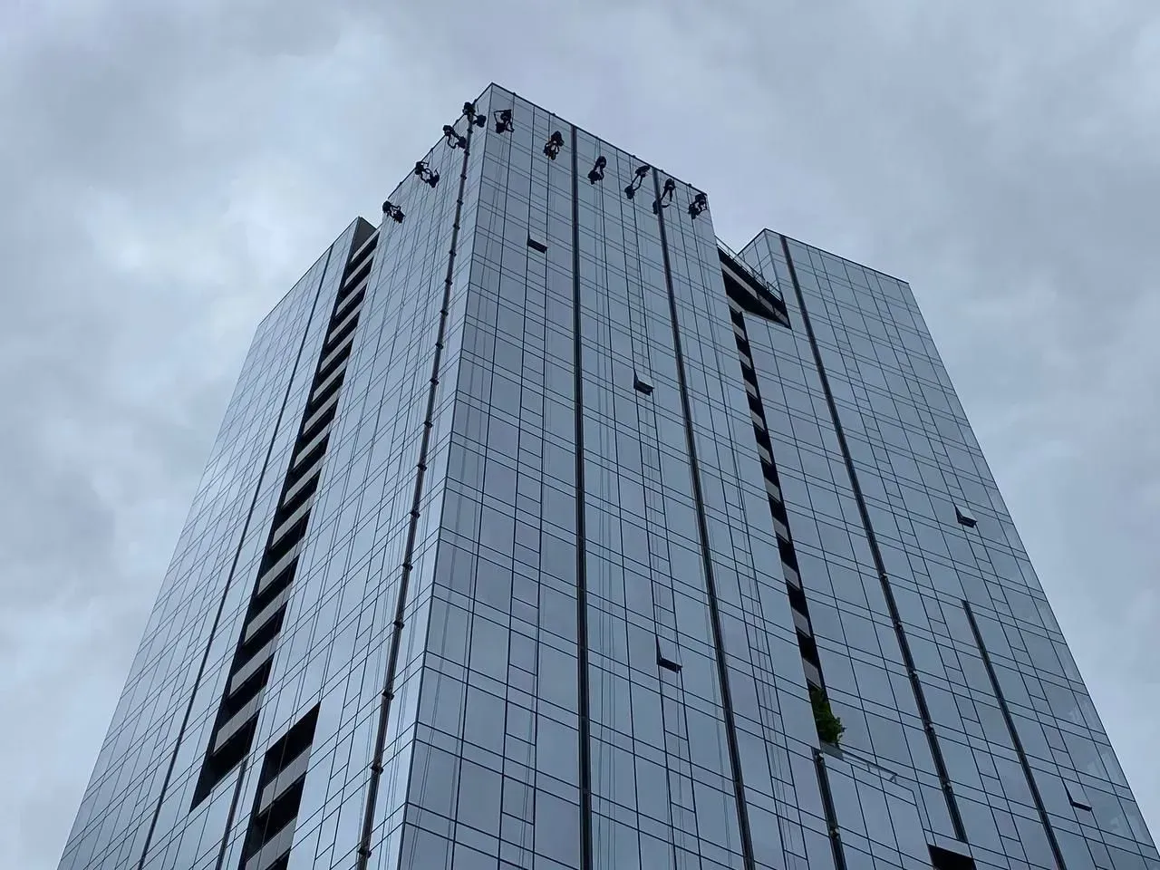 A tall, modern skyscraper with a reflective glass facade against a cloudy sky.