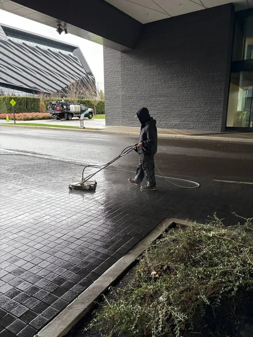 Worker in green uniform power washing stone stairs.