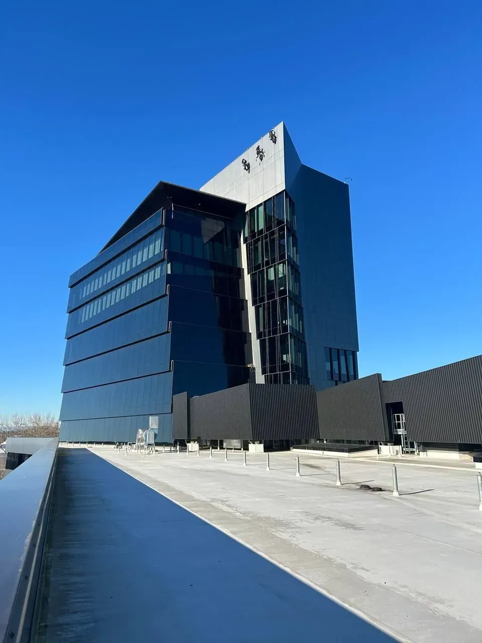 Two window washers in a suspended platform, cleaning a skyscraper's glass exterior, high above the cityscape.