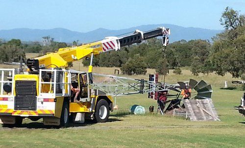 A Yellow Truck with a Crane Attached to it is Parked in a Grassy field — Wetzler Pty Ltd In Marmor QLD