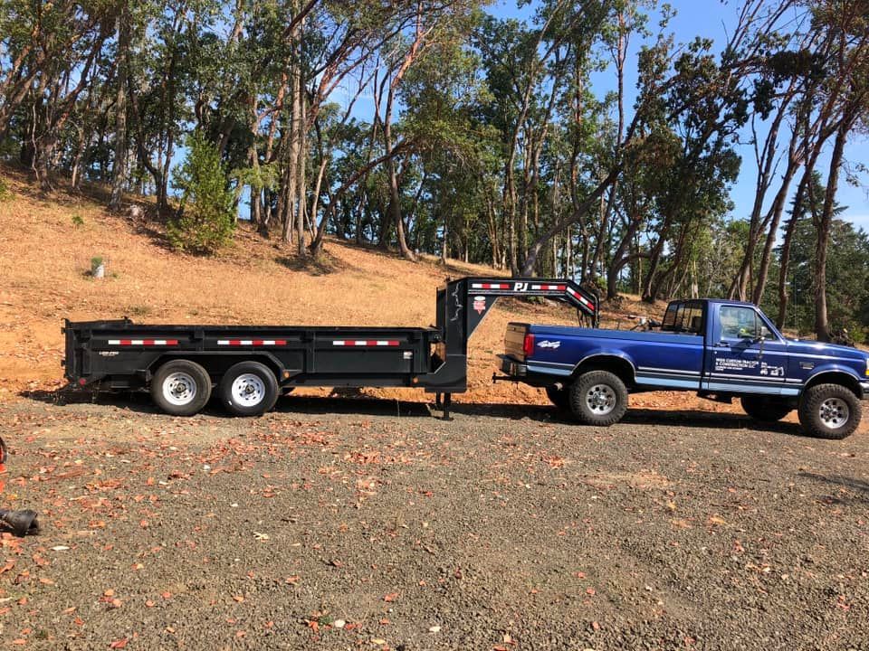 Red excavator and yellow bulldozer on a cleared dirt path under a blue sky.