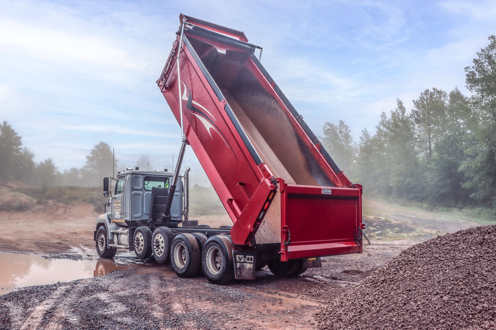 Red excavator and yellow bulldozer on a cleared dirt path under a blue sky.