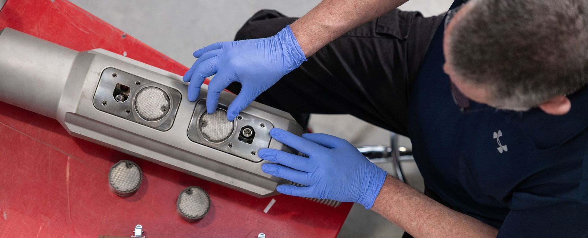 A man wearing blue gloves is working on a machine.