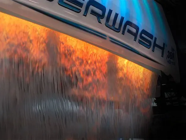 Water flowing from a car wash machine with orange and blue lights illuminating it.