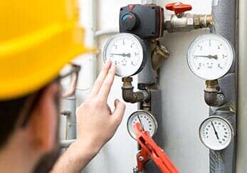 Technician checking pressure meters for house heating system— heater repair in Tampa, FL