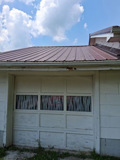 A white garage door with a brown roof on a sunny day.