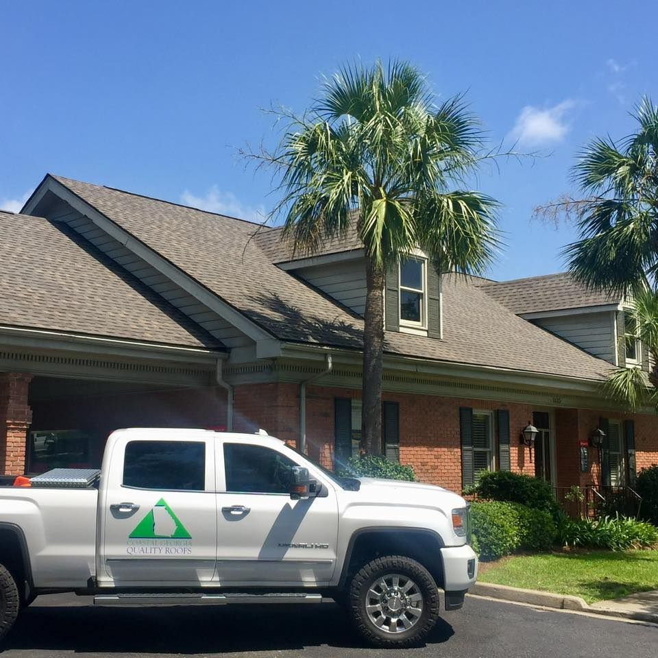 White utility truck parked in front of a brick apartment building with palm trees and blue sky