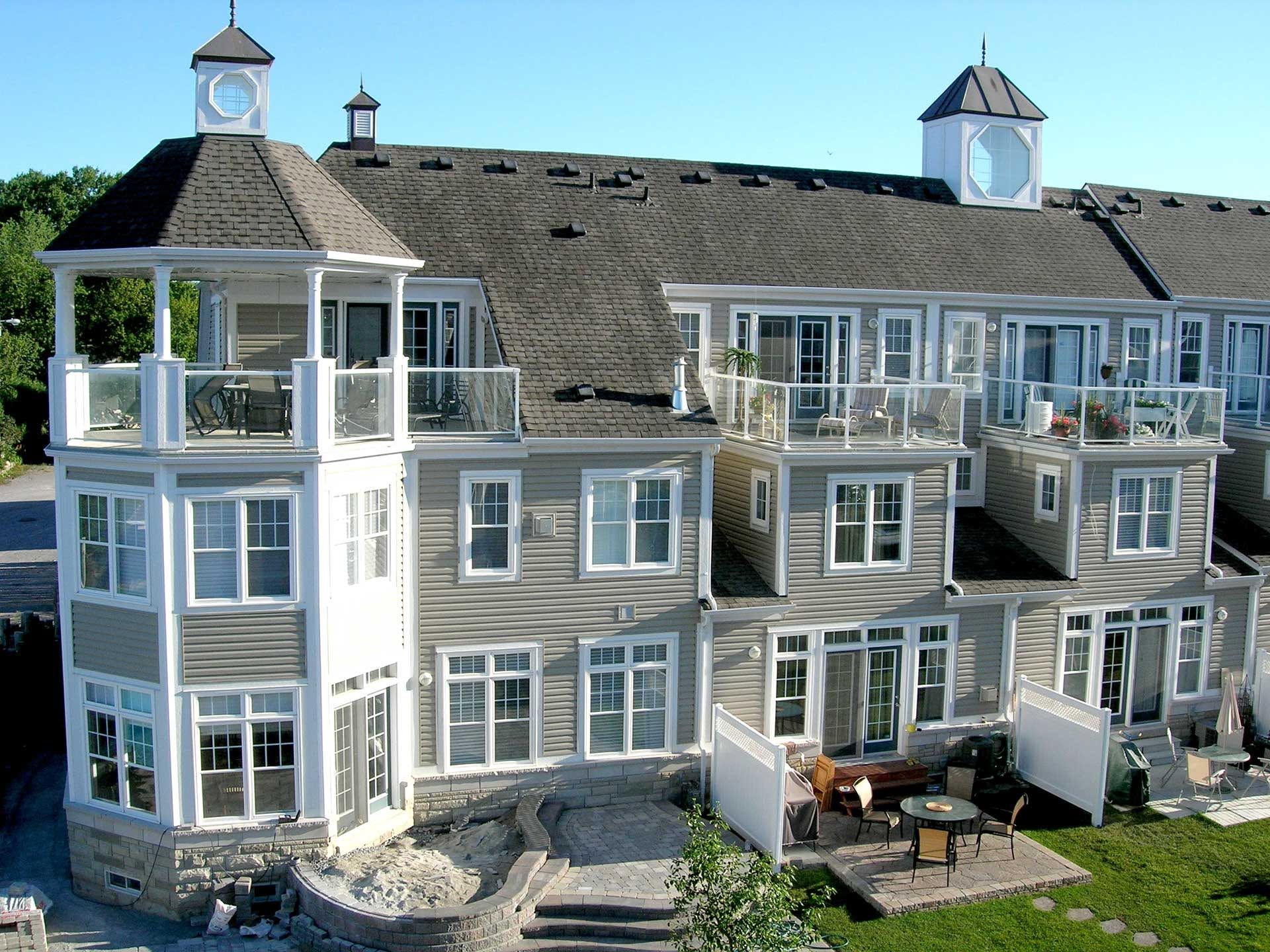 Aerial view of a modern house with a brown roof and green lawn in a suburban area