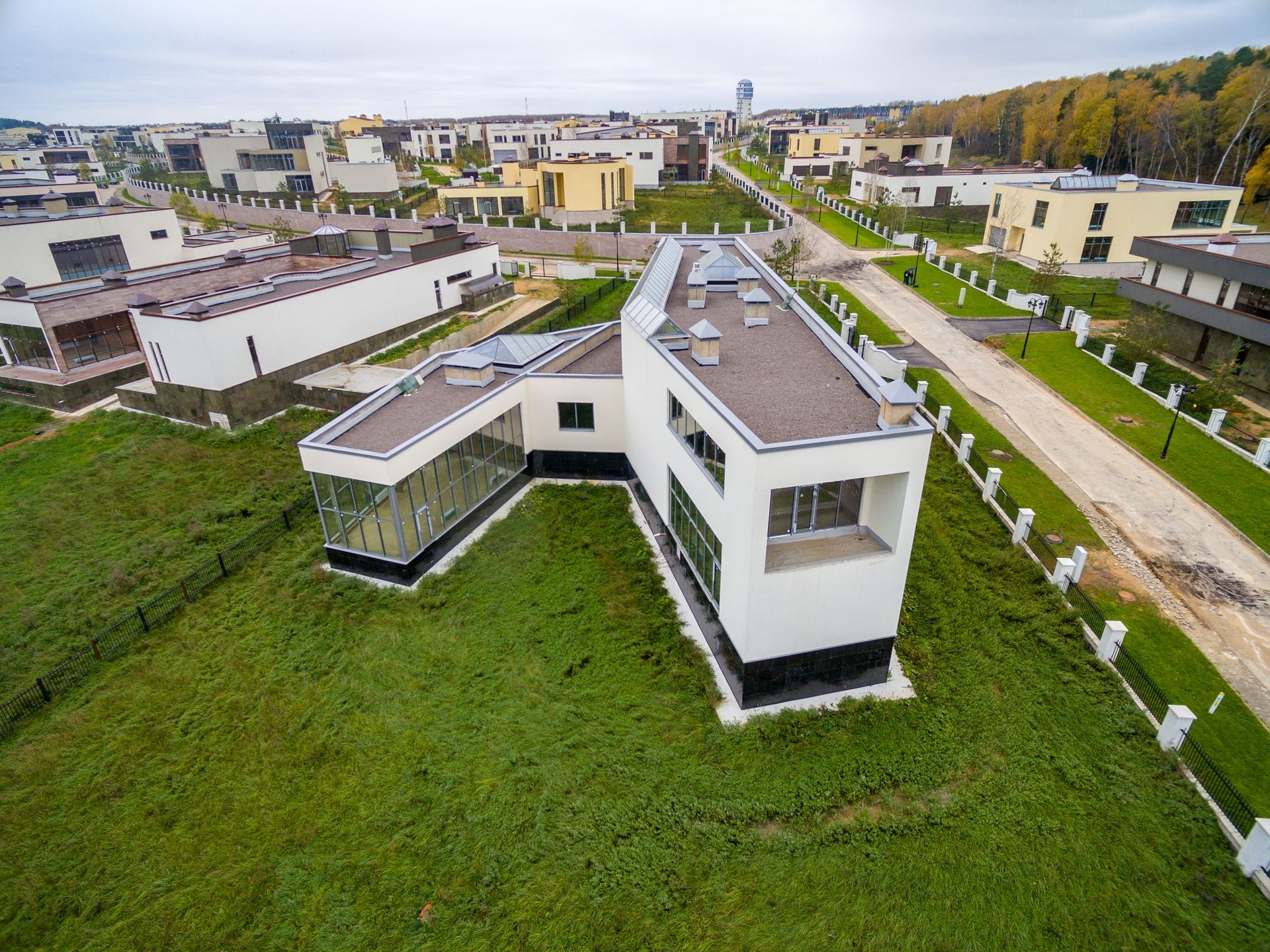 Aerial view of modern white houses in a residential neighborhood with green lawns and paved roads