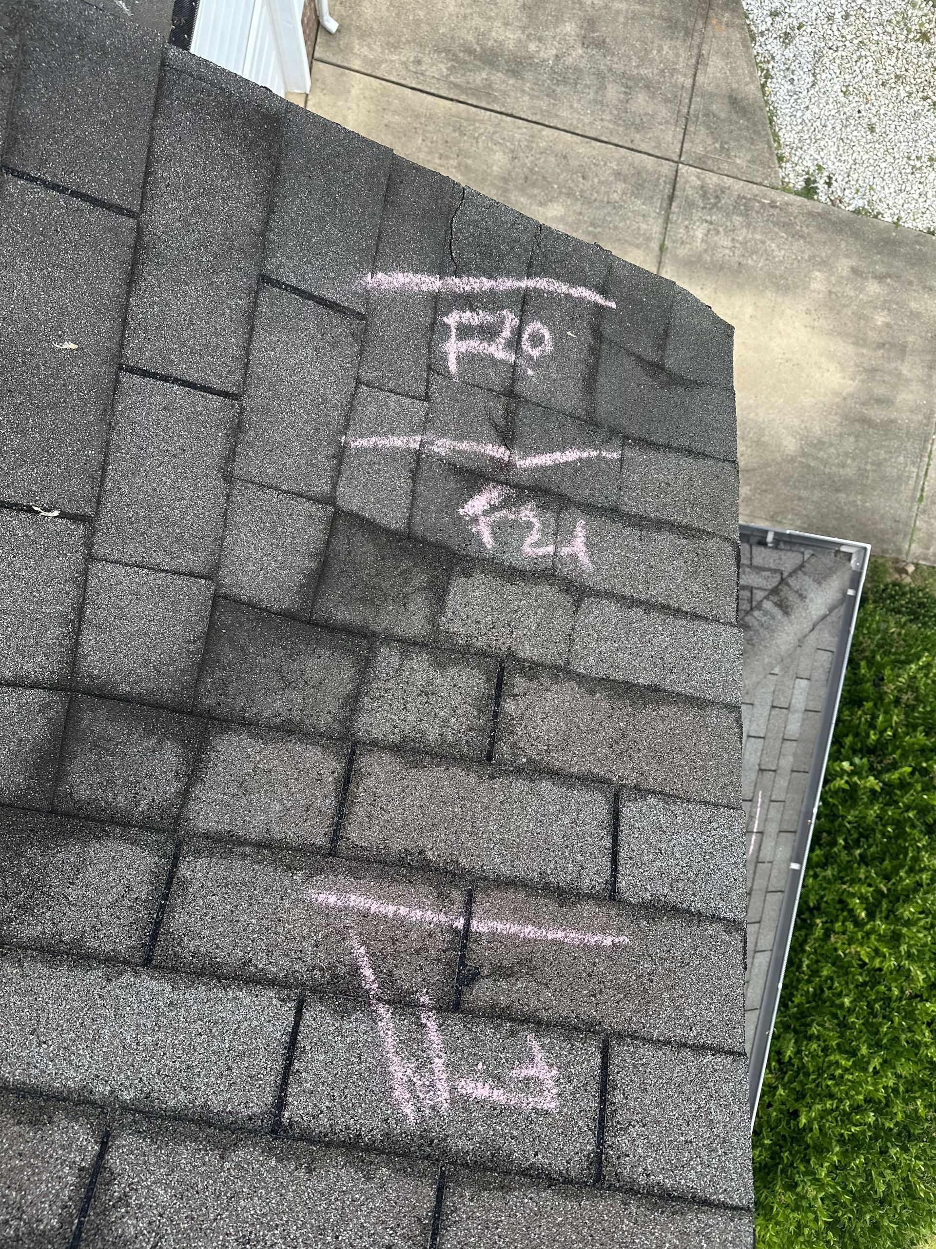 Roof under repair with workers and plywood sheets on a house in a suburban neighborhood.