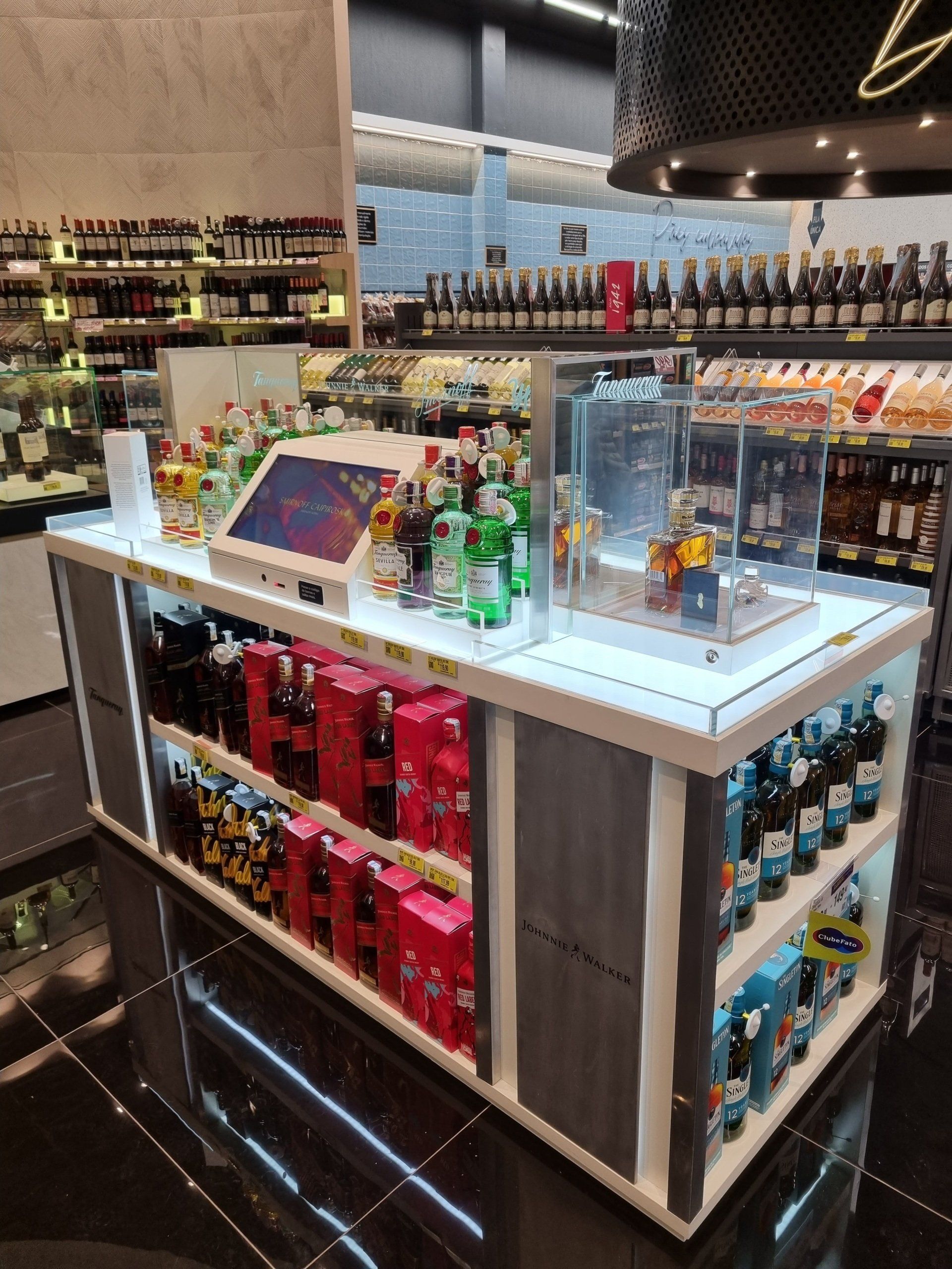Uma grande mesa em uma loja cheia de garrafas de álcool e um tablet.