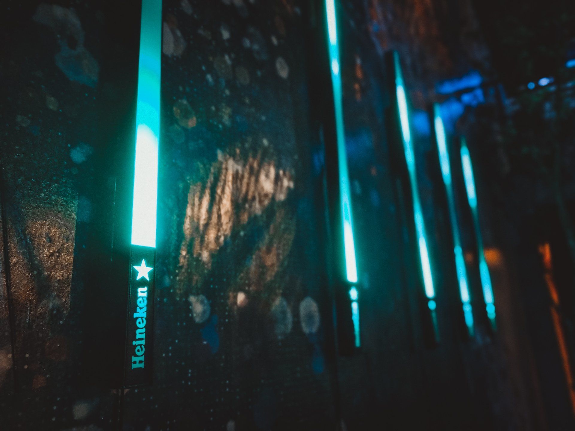 Uma fileira de garrafas de Heineken iluminadas no escuro.