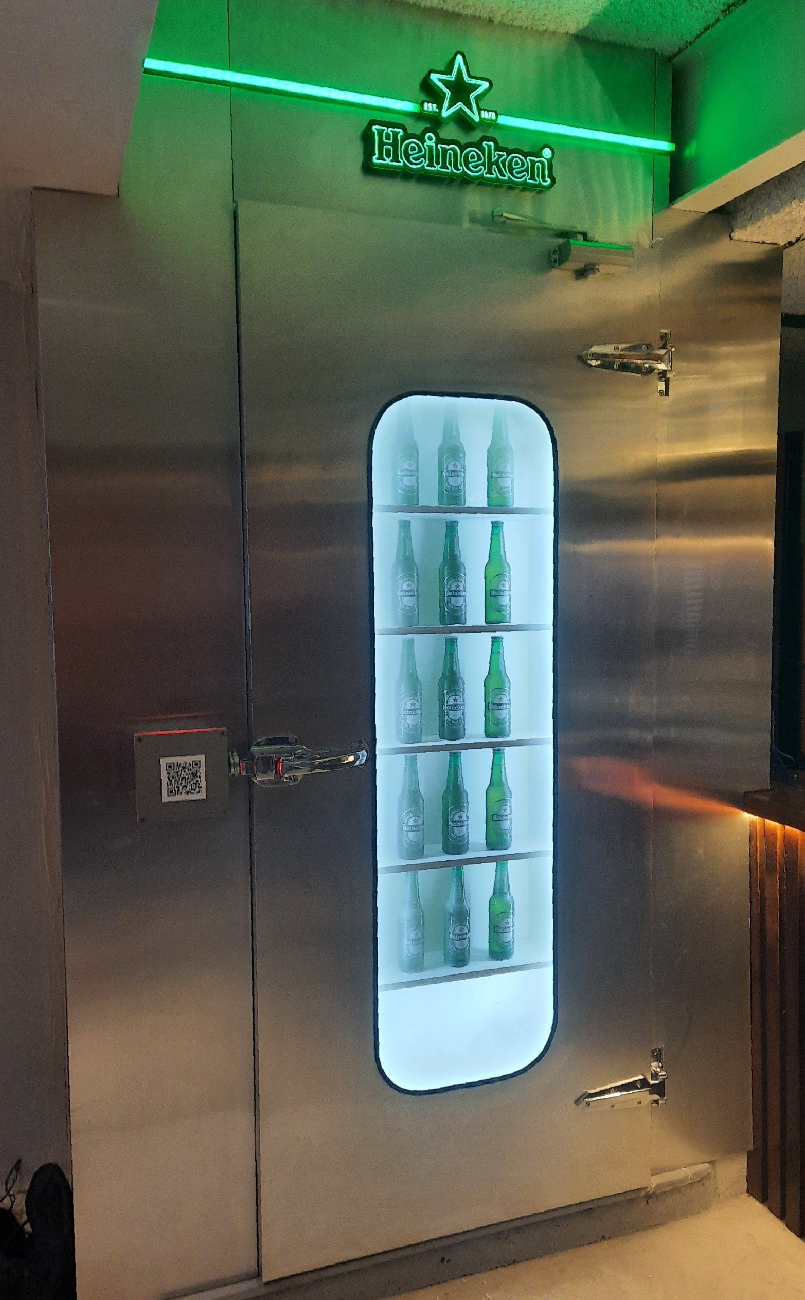 Uma geladeira de aço inoxidável com garrafas de cerveja dentro.