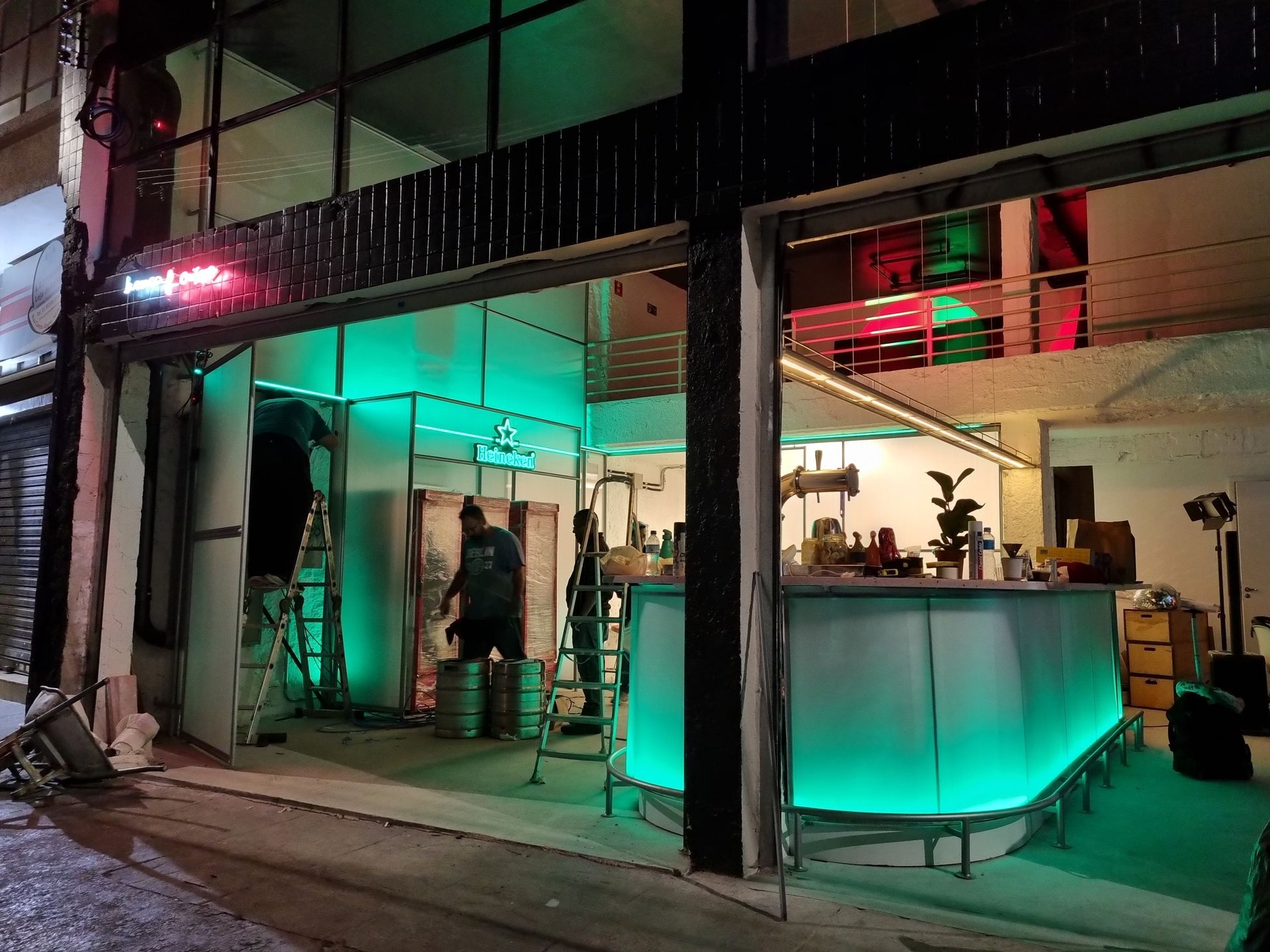 Um bar com luzes verdes está sendo construído em frente a um prédio.