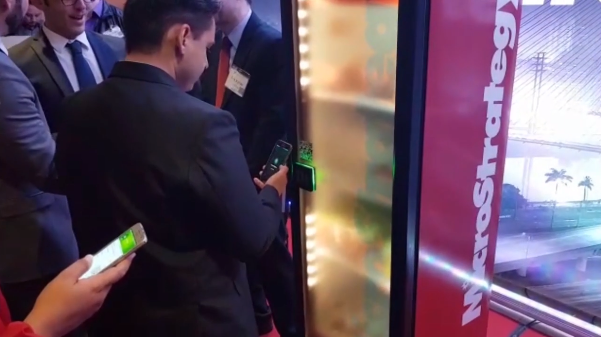 Um grupo de pessoas está em volta de uma máquina de venda automática.