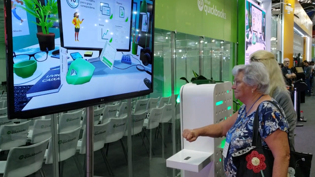 Uma mulher está jogando videogame em uma tela grande.