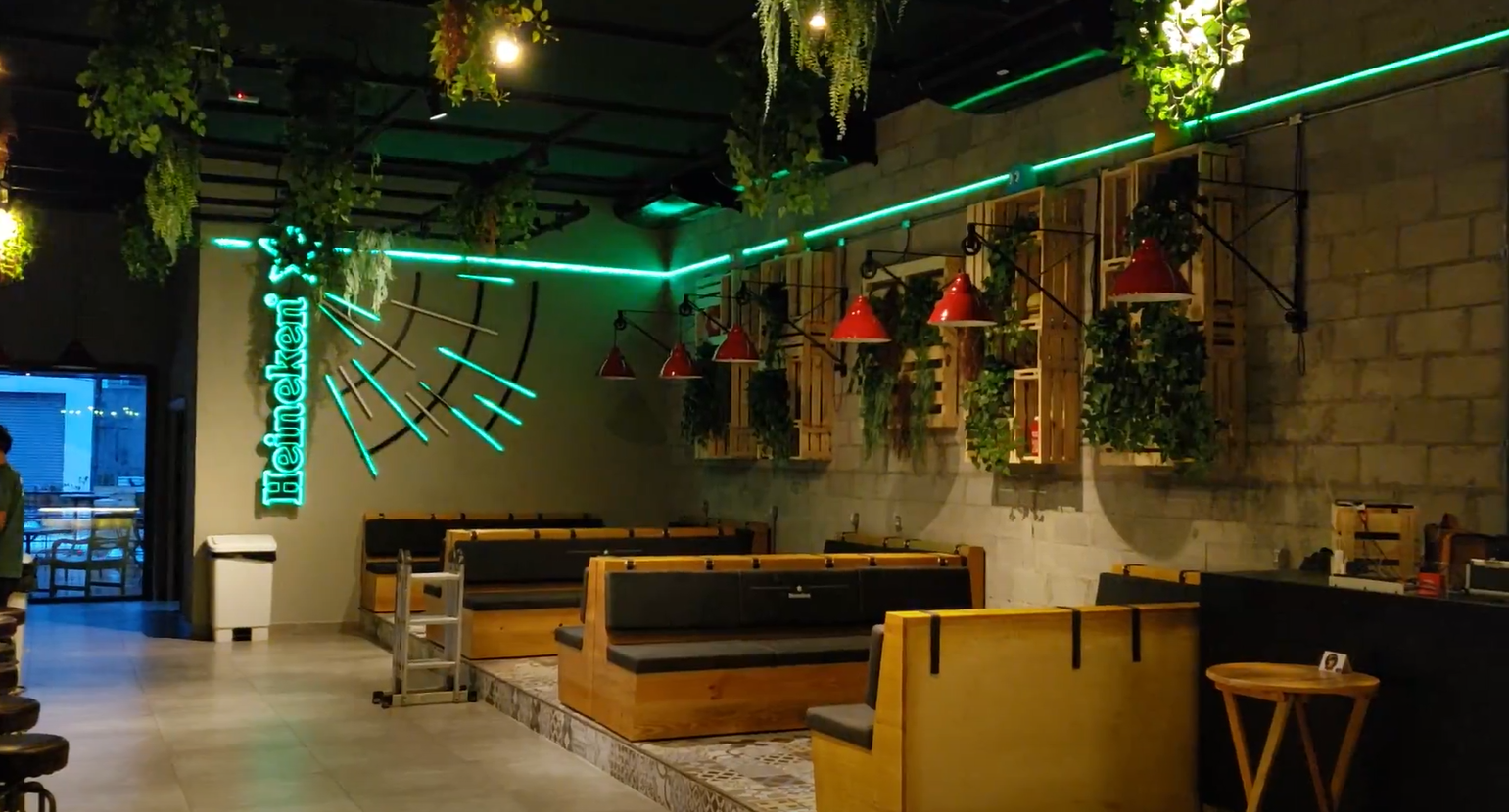 Um restaurante com muitos móveis e luzes verdes nas paredes.