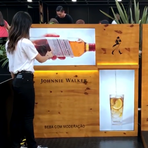 Uma mulher está em frente a uma placa da Johnnie Walker
