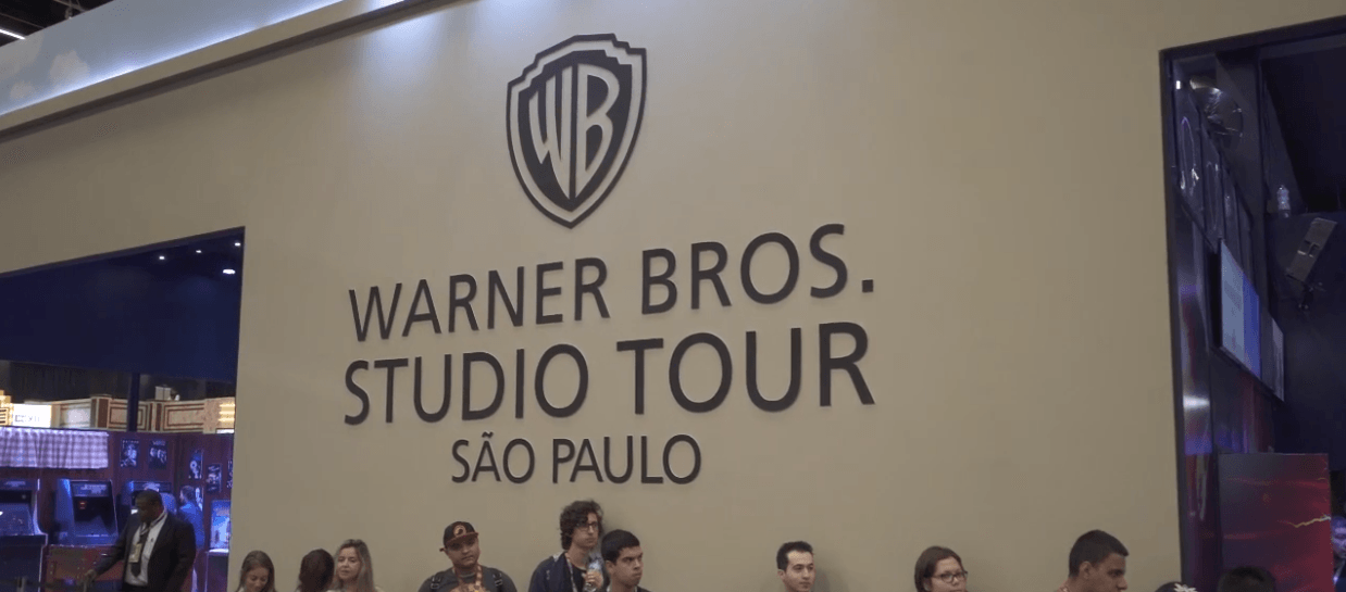 Um grupo de pessoas está em frente a uma placa que diz warner bros studio tour são paulo