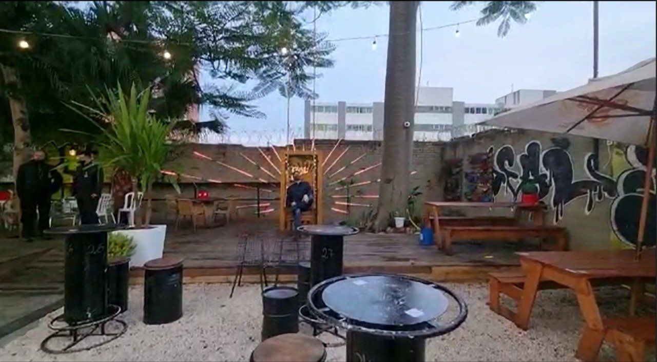 Um pátio com mesas, cadeiras e guarda-sóis em um parque.