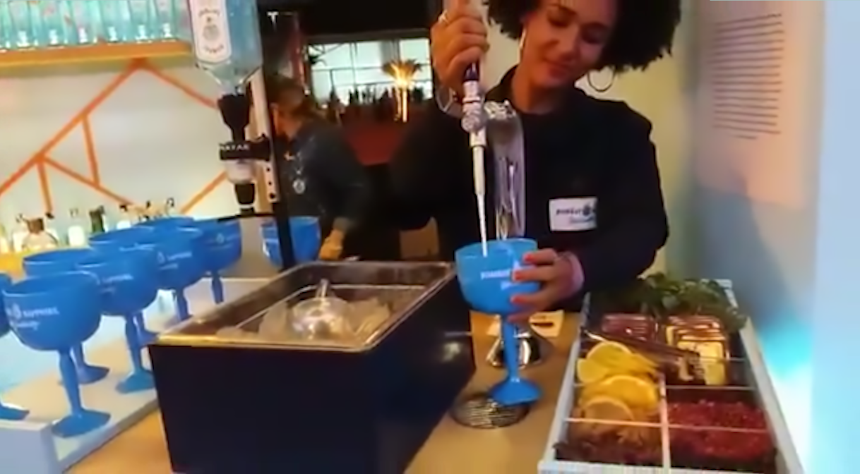 Uma mulher está servindo uma bebida em um copo azul