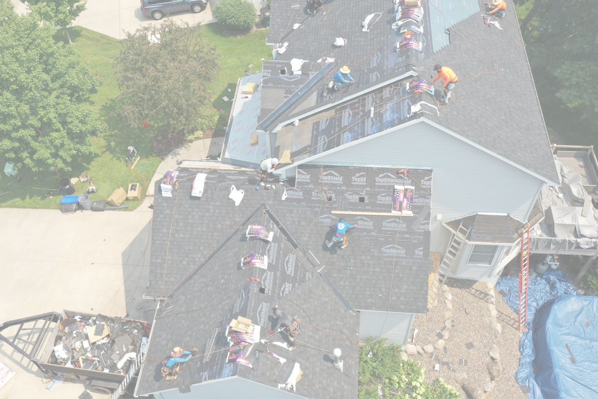 Roof replacement cost Minnesota example showing roofing crew installing new shingles on residential 